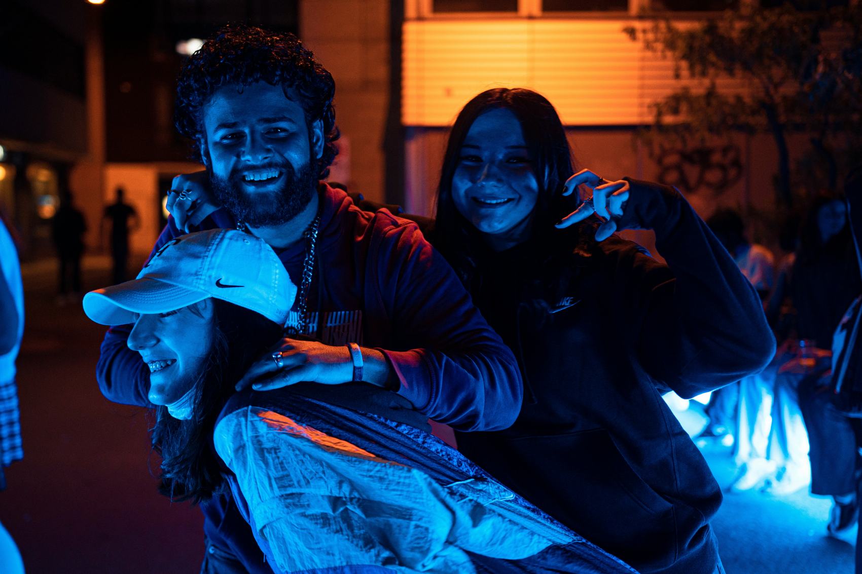 Three guests posing together in blue event lighting