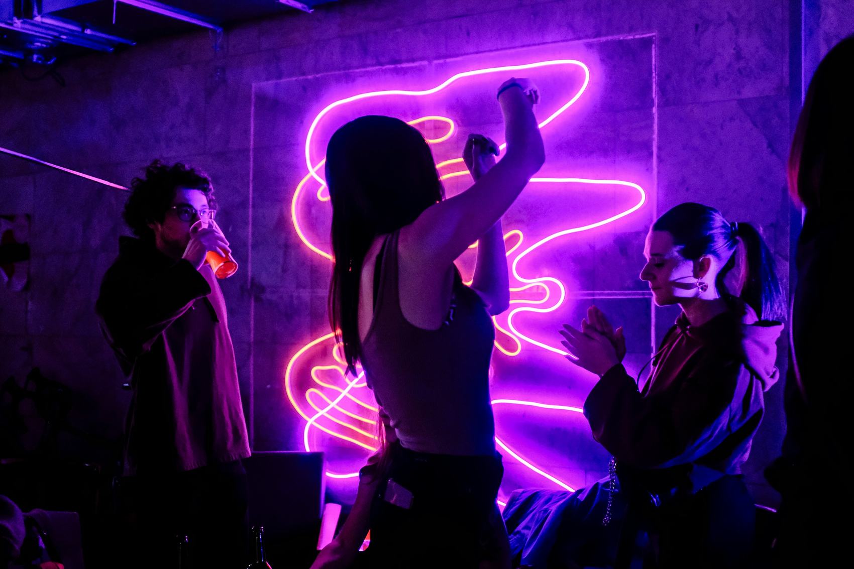 Guests dancing in front of a magenta neon artwork