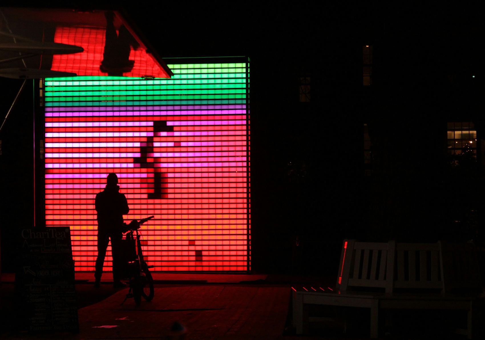 A silhouette in front of a large animated colour-block LED wall