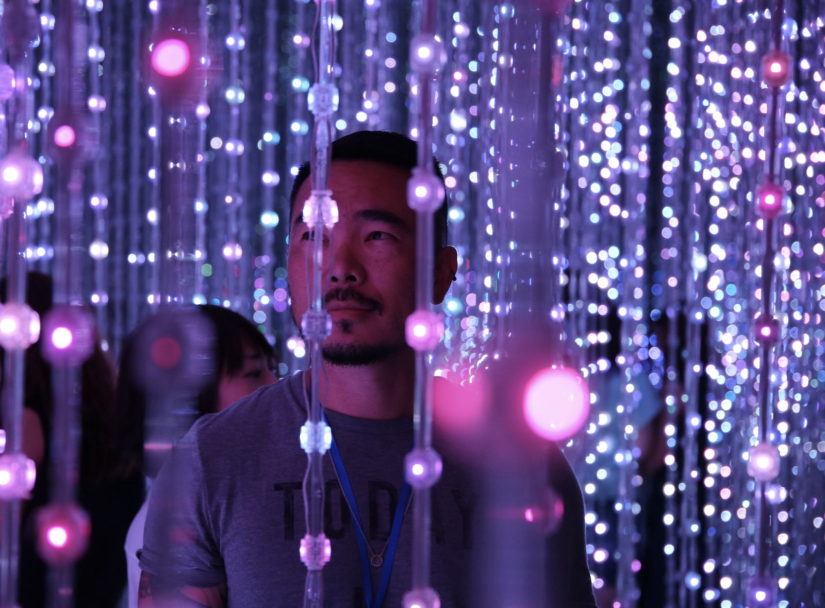 A visitor standing inside hanging strands of crystal-like lights