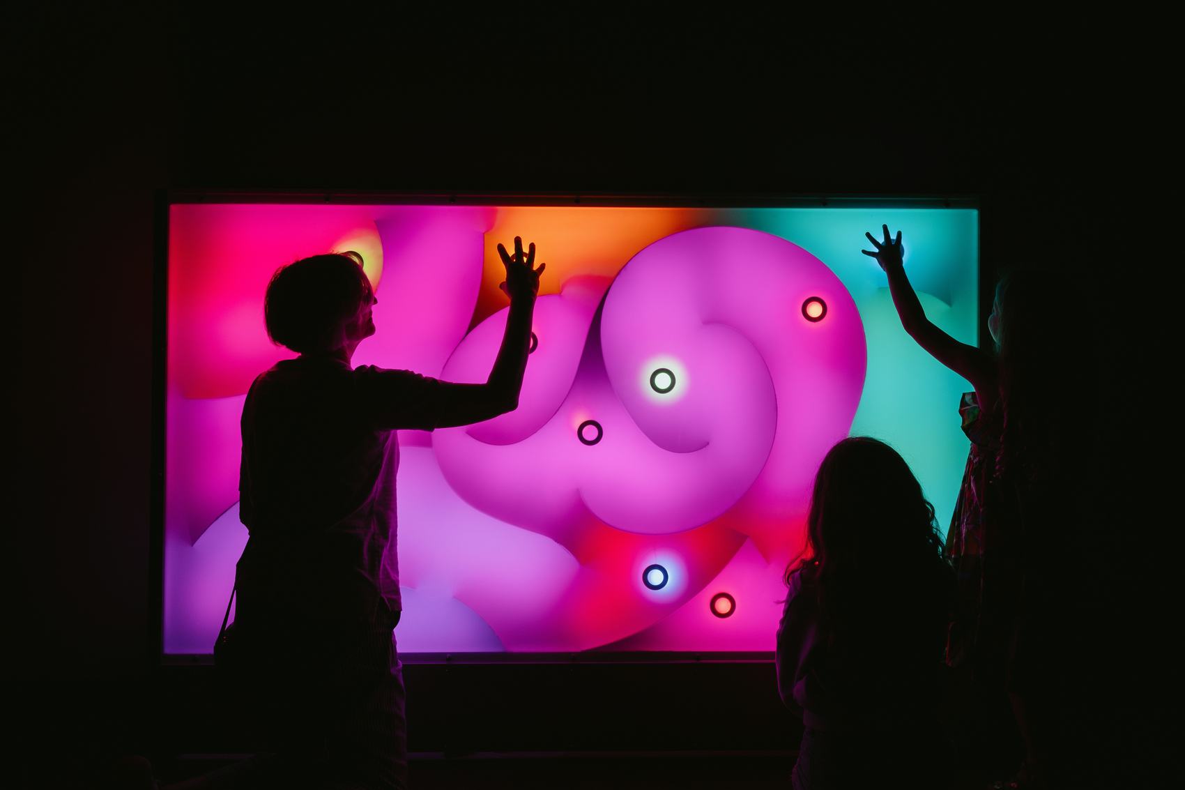 Guests pressing a large illuminated interactive wall at a live event